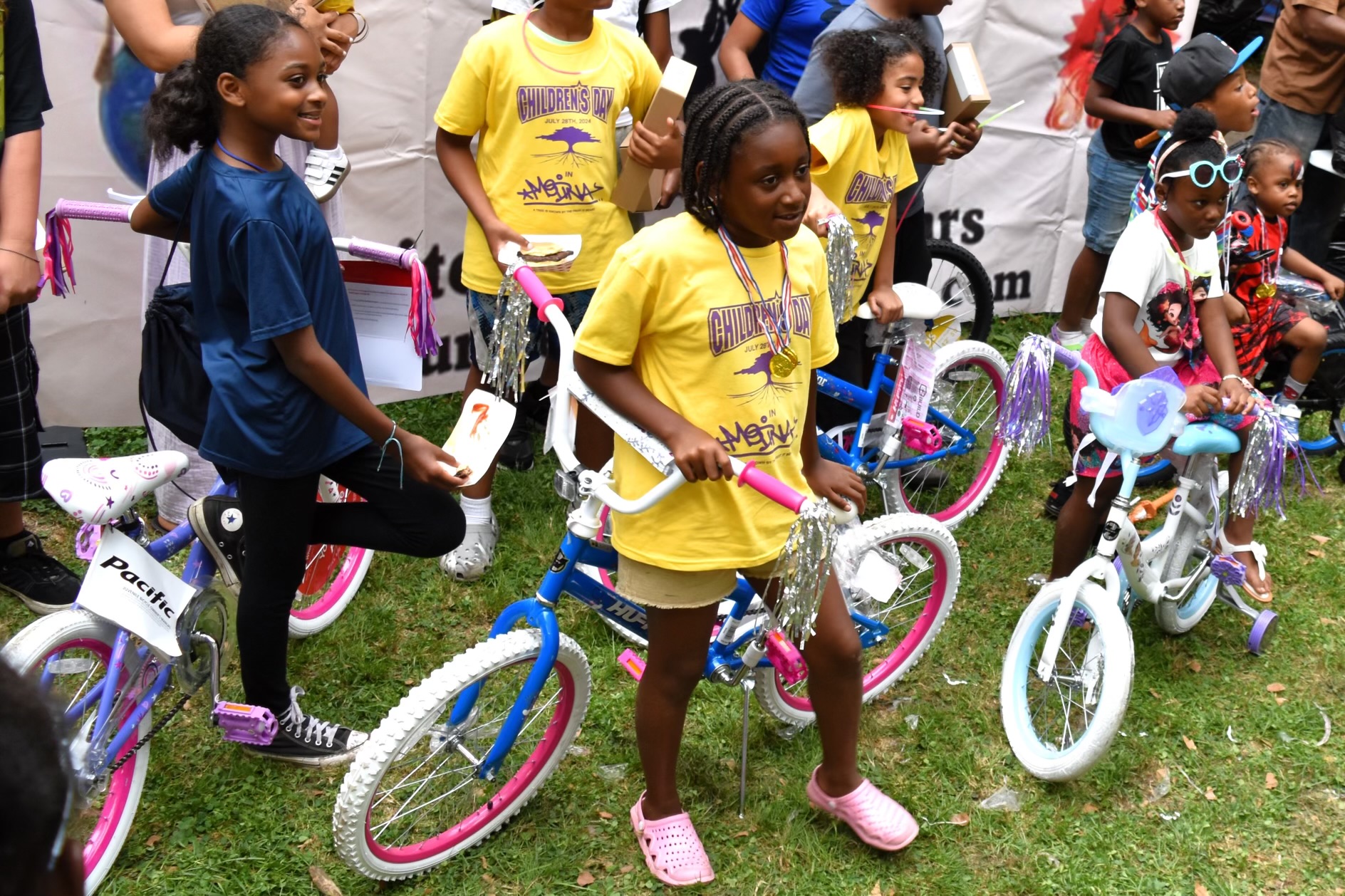 Children standing with bicycles in yellow Children’s Day shirts
