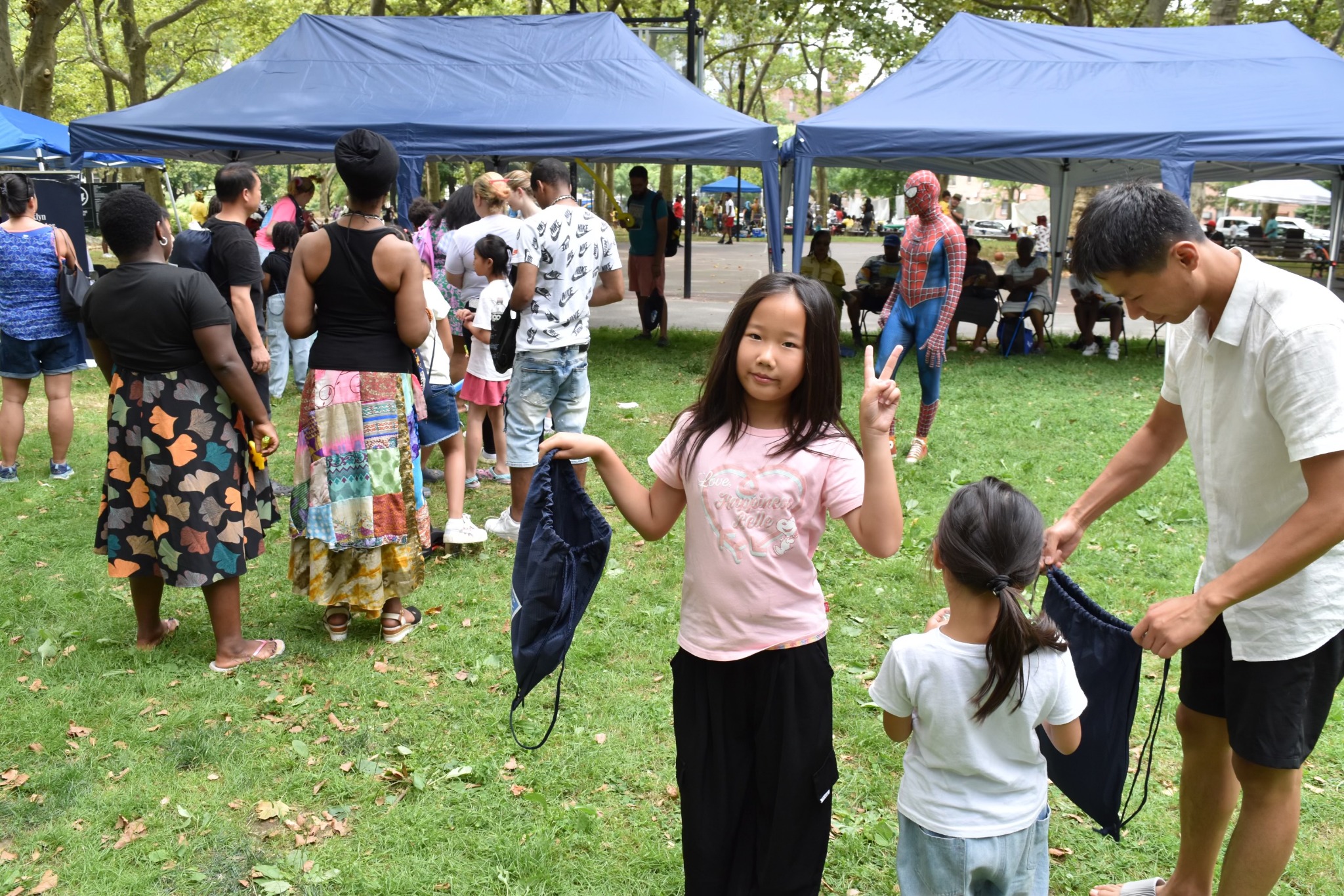 A child holding a giveaway bag with the Children’s Day event behind her